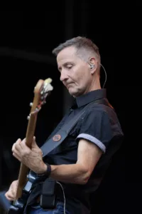 Bassist Jürgen Wernet spielt konzentriert seinen Bass vor dem dunklen Bühnenhintergrund.