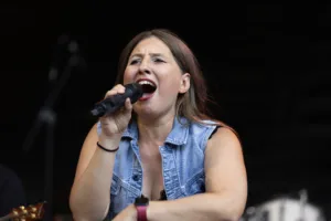 Sängerin Maren Disch singt mit dem Handmikrofon vor dem dunklen Hintergrund der Bühne.