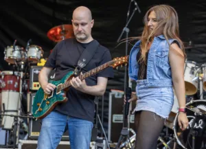 Gitarrist Alexander Stocker spielt seine grüne E-Gitarre, während Sängerin Maren Disch neben ihm steht.