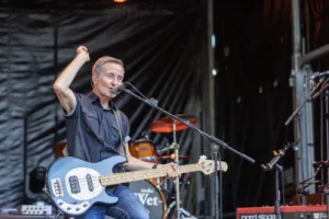 Bassist Jürgen Wernet singt am Mikrofon und hebt eine Faust, während sein Bass vor ihm hängt.