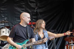 Gitarrist Alexander Stocker spielt seine E-Gitarre, während Sängerin Maren Disch neben ihm den Arm ausstreckt.