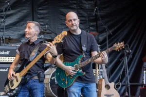 Bassist Jürgen Wernet und Gitarrist Alexander Stocker spielen Seite an Seite vor dem schwarzen Bühnenvorhang.
