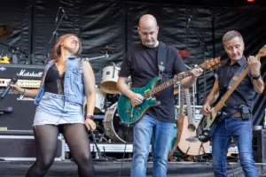Sängerin Maren Disch steht zwischen Gitarrist Alexander Stocker und Bassist Jürgen Wernet, die gemeinsam auf der Bühne spielen.