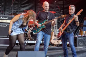 Sängerin Maren Disch beugt sich zwischen Gitarrist Alexander Stocker und Bassist Jürgen Wernet nach vorn.