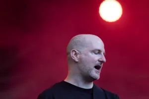Gitarrist Alexander Stocker steht im roten Bühnenlicht vor einem hell leuchtenden Scheinwerfer.