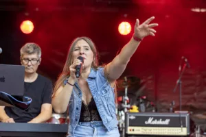 Sängerin Maren Disch singt ins Handmikrofon und streckt einen Arm aus, während Keyboarder Ralf Rees hinter ihr spielt.