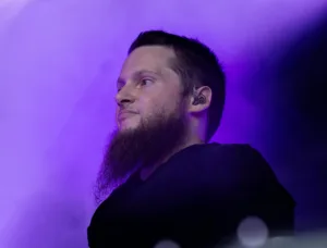 Posaunist Simon Kräuter steht seitlich im violetten Bühnennebel, mit zurückhaltender Beleuchtung und dunklem Hintergrund.