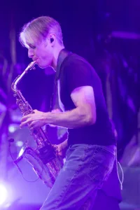 Saxofonist Max Marlier beugt sich beim Spielen nach vorn, während violettes Licht und Nebel seine Bewegung hervorheben.