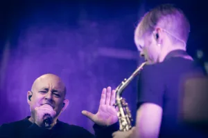 Sänger Sascha Spitz singt neben Saxofonist Max Marlier, der ihm unter blau-violettem Bühnenlicht den Rücken zuwendet.