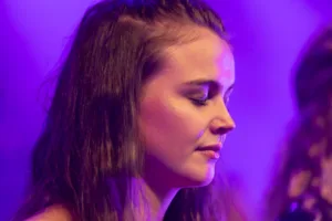 Sängerin Marleen Hoppe steht im violetten Bühnenlicht im Profil, während eine zweite Sängerin am linken Bildrand angeschnitten ist.