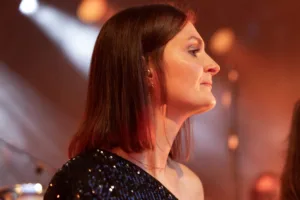 Sängerin Tamara Hoppe blickt im warmen Seitenlicht zur Bühne, ihr schwarzes Paillettenoberteil hebt sich vom Hintergrund ab.