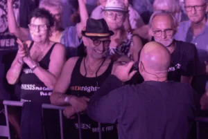 Sänger Sascha Spitz steht mit dem Rücken zur Kamera direkt vor der Absperrung und begegnet dem Publikum am Bühnenrand.