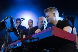 Keyboarder Tim Giron und Sänger Sascha Spitz stehen gemeinsam hinter dem roten Keyboard, von kräftigem blauem Gegenlicht umgeben.