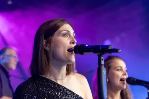 Sängerinnen Tamara Hoppe und Marleen Hoppe singen an benachbarten Mikrofonen, während violetter Bühnennebel hinter ihnen aufzieht.