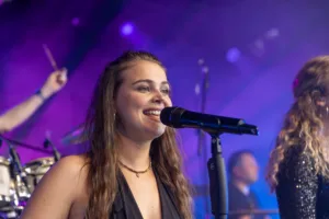 Sängerin Marleen Hoppe singt ins Mikrofon, während violettes Licht ihr Gesicht und den Bühnennebel färbt.