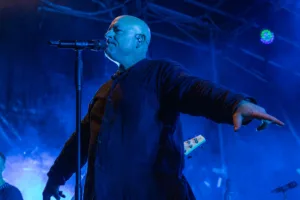 Sänger Sascha Spitz singt am Mikrofon und streckt eine Hand zum Publikum aus, während tiefblaues Bühnenlicht hinter ihm leuchtet.
