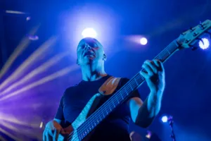 Bassist Steffen Vogt spielt aus tiefer Perspektive in die Kamera, während ein heller Scheinwerfer über seinem Kopf aufflammt.