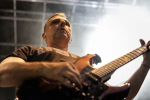 Gitarrist Sascha Happle spielt aus extremer Untersicht, während helles Gegenlicht die Gitarre und seine Silhouette hervorhebt.