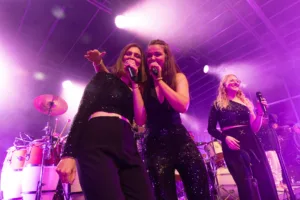 Sängerinnen Tamara Hoppe und Marleen Hoppe singen Schulter an Schulter, während eine dritte Sängerin hinter ihnen am Mikrofon steht.