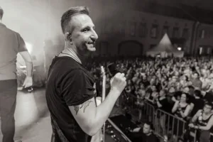 Gitarrist Sascha Happle steht im Schwarzweißbild am Bühnenrand und blickt über die Schulter zum dicht gedrängten Publikum auf dem Platz.